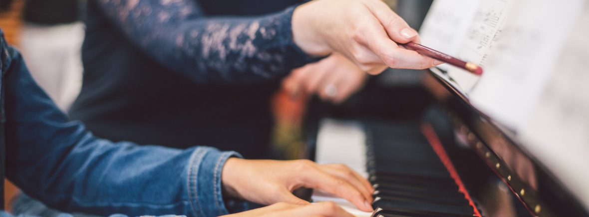 Female teacher shows child how to play the piano